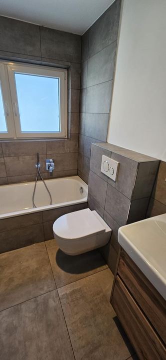Bad mit Badewanne & Wand-WC – Graue Großformatfliesen